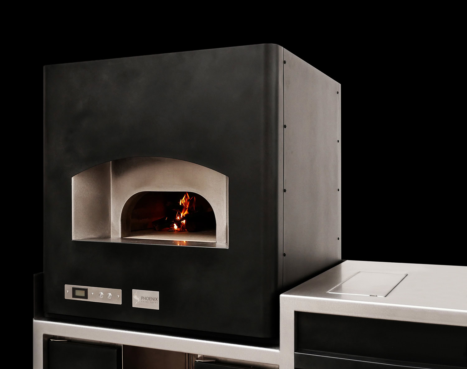 Compact benchtop oven in dark steel with an arched mouth and a fire burning inside